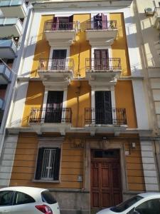 żółty budynek z balkonami i biały samochód zaparkowany przed budynkiem w obiekcie La luminaria w mieście Bari