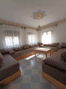 een woonkamer met banken, een tafel en ramen bij appartement 2chambres et un salon in Chefchaouene