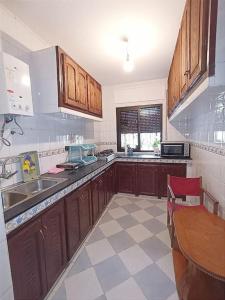 een keuken met houten kasten, een wastafel en een tafel bij appartement 2chambres et un salon in Chefchaouene