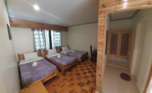 um pequeno quarto com 2 camas e uma janela em Rusty Nail Inn and Cafe em Sagada