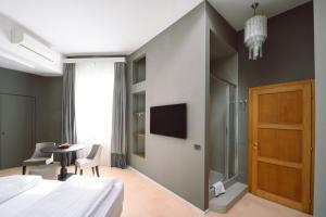 - une chambre avec un lit, une table et une télévision dans l'établissement Palazzo Froussard B&B and Living, à Lucques