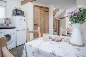 uma cozinha com uma mesa com um vaso de flores em The Old School Cottage Ship Farm - 1 Bedroom - Rhossili em Rhossili