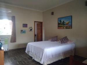 um quarto com uma cama branca num quarto em Toca do Guaiamum I em Ubatuba