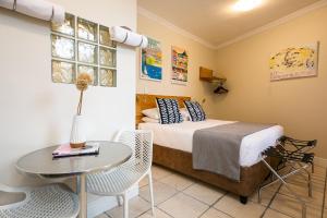 1 dormitorio con 1 cama, mesa y sillas en The Charles Cafe & Guesthouse, en Ciudad del Cabo