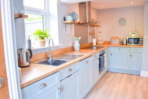 a kitchen with white cabinets and a sink at Avocet - Suffolk Coastal Escapes in Pakefield