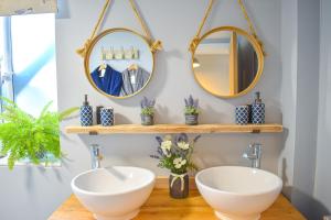 two sinks in a bathroom with mirrors on the wall at Avocet - Suffolk Coastal Escapes in Pakefield