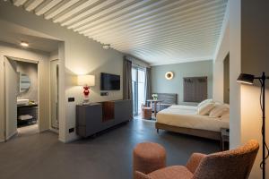 a bedroom with a bed and a television and chairs at VIS Urban Suites&Spa in Bari