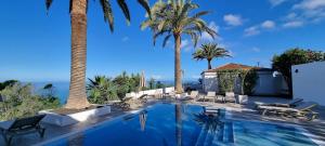 a swimming pool with palm trees and chairs at Maresía Village in Los Realejos