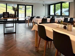 a dining room with tables and chairs and windows at k1 sporthotel - Bike & Ski inklusive Hotel in Kurort Oberwiesenthal