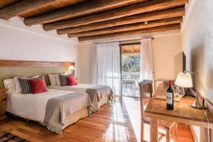 a bedroom with two beds and a table and a window at Lares De Chacras in Chacras de Coria +37 photos