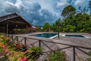 a swimming pool with a wooden deck and flowers at Borneo Sepilok Rainforest Resort in Sepilok
