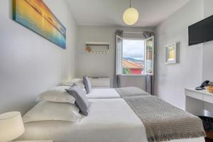 a white bedroom with a bed and a window at Vila Camacho Guest House in Funchal