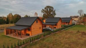 a row of wooden homes with black roofs at Ostoja Ldzań 