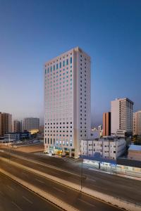 un edificio blanco alto al lado de una autopista en Makarem Al Bait Al Azizia Hotel, en La Meca
