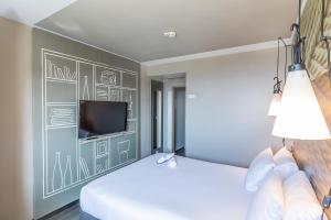 a bedroom with two beds and a tv on a wall at Hotel ibis Porto Gaia in Vila Nova de Gaia