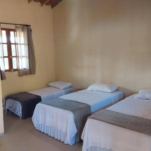 three beds in a room with a window at Vila Sincorá - Chalé para 4 pessoas com cozinha a 2 km da portaria da Cachoeira do Buracão in Ibicoara