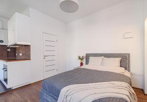 1 dormitorio blanco con 1 cama grande y cocina en Welcoming Studio in historic Vilnius with free parking by URBAN RENT en Vilna