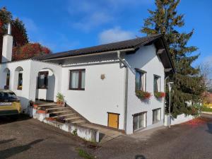 a white house with a porch and a driveway at Pension Welserhof in Wilfersdorf