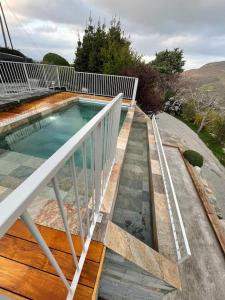 a swimming pool on a wooden deck with a white railing at Gites en Ardèche avec Piscine et vue magnifique sur la vallée in Rochessauve