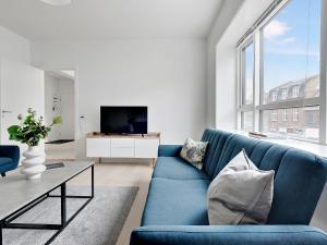 ein Wohnzimmer mit einem blauen Sofa und einem TV in der Unterkunft Sanders Fjord - Smart One-Bedroom Apartment In Center of Roskilde in Roskilde