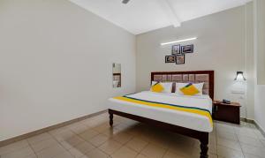 a bedroom with a large bed with yellow pillows at Itsy By Treebo - Green Villaa 2 Km From Pondicherry Railway Station in Puducherry