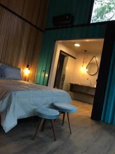 a bedroom with a bed and two tables in front of a tub at Pousada Sitio Raizes in Siderópolis
