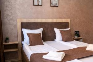 1 dormitorio con 2 camas con sábanas blancas y almohadas marrones en Luxor Apartment, en Velingrad
