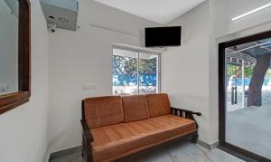 a brown couch in a room with a window at Itsy By Treebo - Green Villaa 2 Km From Pondicherry Railway Station in Puducherry