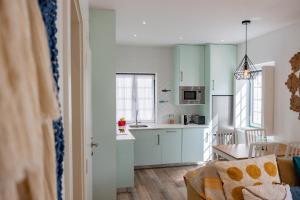 a kitchen with white cabinets and a table in a room at Feel Nazaré - Abegoarias 62 in Nazaré