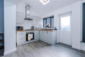 a kitchen with white cabinets and a window at Haydock Gold by Prime Stay in Golborne