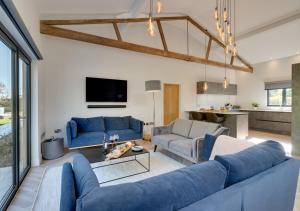 a living room with blue couches and a tv at Daisys Barn in Mattishall