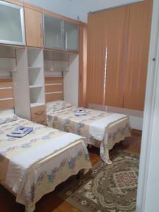 a room with two beds and a rug at Apartamento 2 dormitórios, wifi, ponta da praia, predio em frente ao mar - Santos in Santos