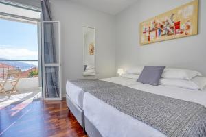 a white bedroom with a bed and a balcony at Vila Camacho Guest House in Funchal