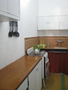 uma cozinha com armários brancos e um balcão de madeira em Artemisa em Piriápolis