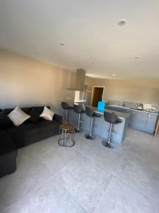 a living room with a black couch and a kitchen at Appleacre Accommodation in Winford