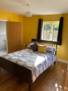 a bedroom with a bed with yellow walls and a window at Appleacre Accommodation in Winford