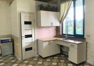 een keuken met witte kasten, een wastafel en een raam bij N_life in Kapchagay