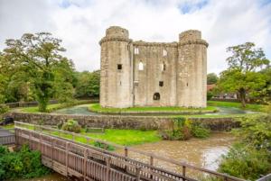 an old castle with a bridge in front of it at Brook House in Nunney