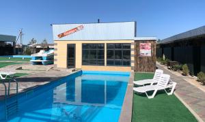 a swimming pool with two white chairs next to a building at Nlife hotel in Kapchagay