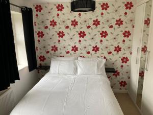 a bedroom with a white bed with red flowers on the wall at Cheerful Home FOR FOOTBALL, DOCKS AND CITY CENTRE in Liverpool