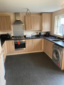 a kitchen with wooden cabinets and a stove top oven at Cheerful Home FOR FOOTBALL, DOCKS AND CITY CENTRE in Liverpool