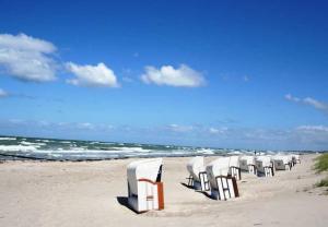 una fila de sillas sentadas en una playa en SONNENDECK App Nr 19 max 4 Pers, en Dierhagen