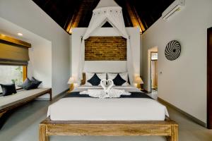 - une chambre avec un grand lit blanc et un mur en briques dans l'établissement Poka Villa & Spa, à Ubud