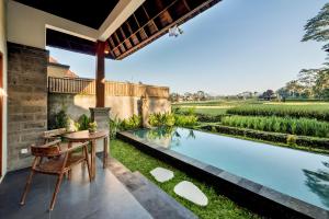 a patio with a table and chairs next to a swimming pool at Poka Villa & Spa in Ubud