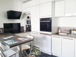 una cucina con mobili bianchi e tavolo di EXIGEHOME-Bel appartement de standing-30 minutes de Paris a Vélizy-Villacoublay