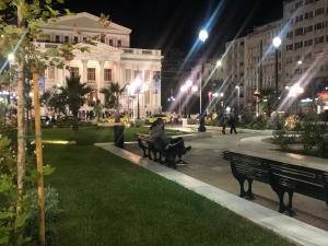 a person sitting on a bench in a park at night at Royal Blue Grand Suite No 1 in Piraeus