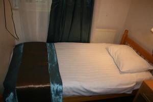 a bedroom with a bed with white sheets and a window at Earls Court Garden Hotel in London