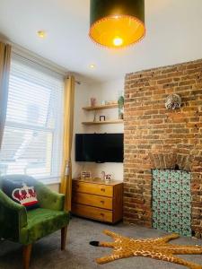 a living room with a brick fireplace and a green chair at Funky 2 Bedroom Apartment In Town Centre in Hastings