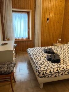 1 dormitorio con 1 cama con 2 zapatillas en Ciasa Giulia, en Auronzo di Cadore