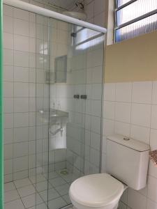 a bathroom with a toilet and a glass shower at Suítes Maresias in São Sebastião